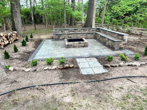Bluestone paver patio with built-in firepit and seating walls in a wooded backyard